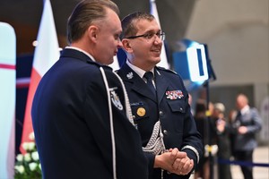 Zdjęcie przedstawia dwóch stojących policjantów w mundurach galowych