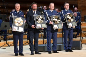 Zdjęcie przedstawia trzech policjantów oraz mężczyznę trzymających złote płyty