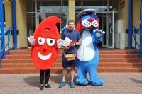 Maskotka policyjna Sznupek i maskotka centrum krwiodawstwa na tle budynku