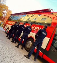 Policjanci czekający na oddanie krwi przed ambulansem do oddawania krwi