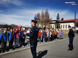 Grupa dzieci słuchająca prelekcji policjantów.